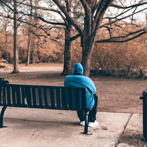 Một người ngồi một mình trên ghế công viên, nhìn đầy suy nghĩ và trầm tư.